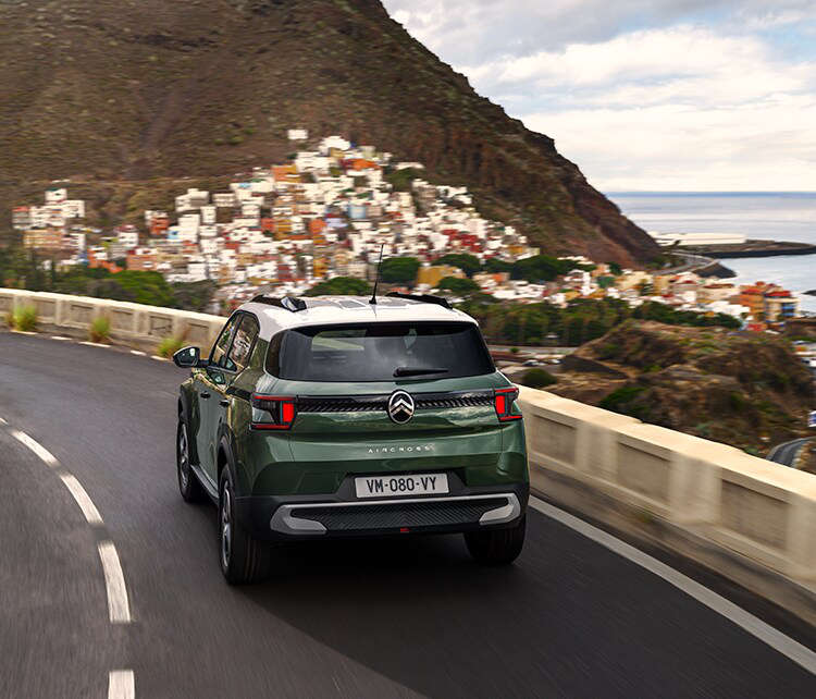 Зелений Citroën C3 Aircross їде по серпантину, вигляд ззаду з лівого боку