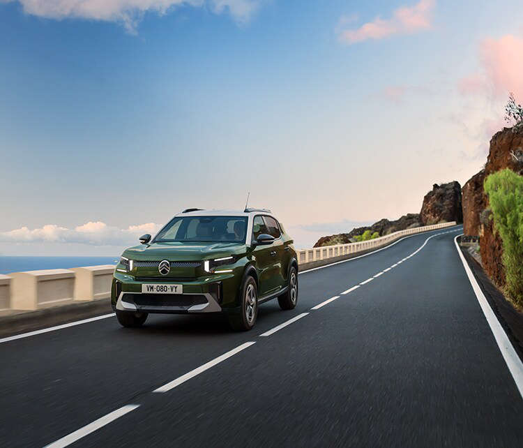 Зелений Citroën C3 Aircross їде по серпантину, вигляд спереду з лівого боку